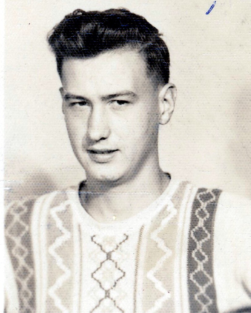 Young man with dark hair wearing a geometric-embroidered sweater in a vintage black-and-white portrait.