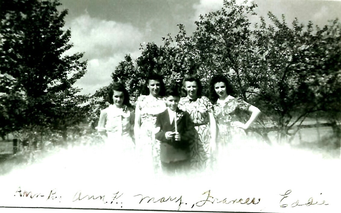 Group of six people (five women and a boy) posing outdoors in a line, with trees in the background; appears to be a vintage black-and-white family photo.