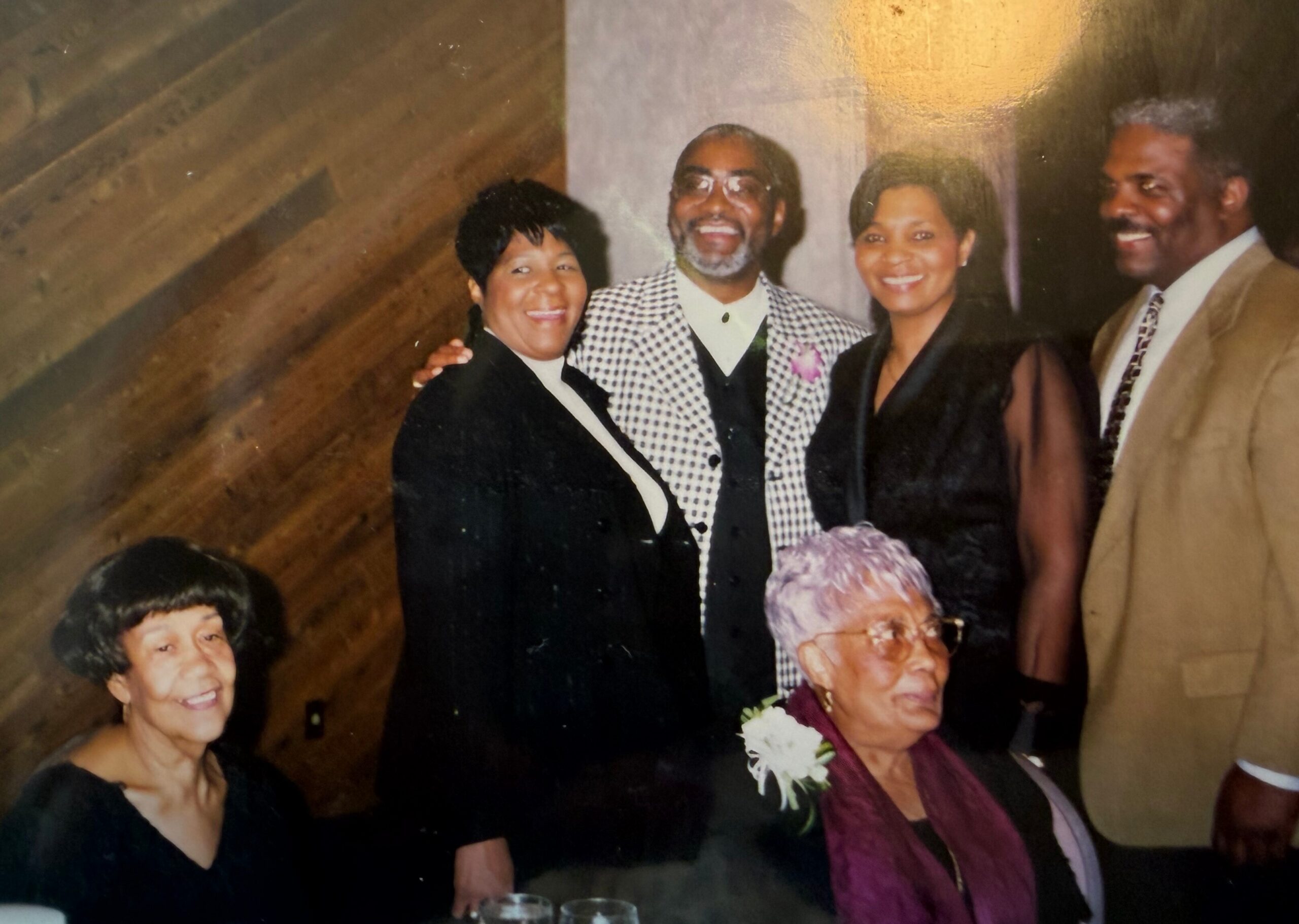 Group of four adults at a formal event posing and smiling for the camera, two women in black dresses and two men in suits.