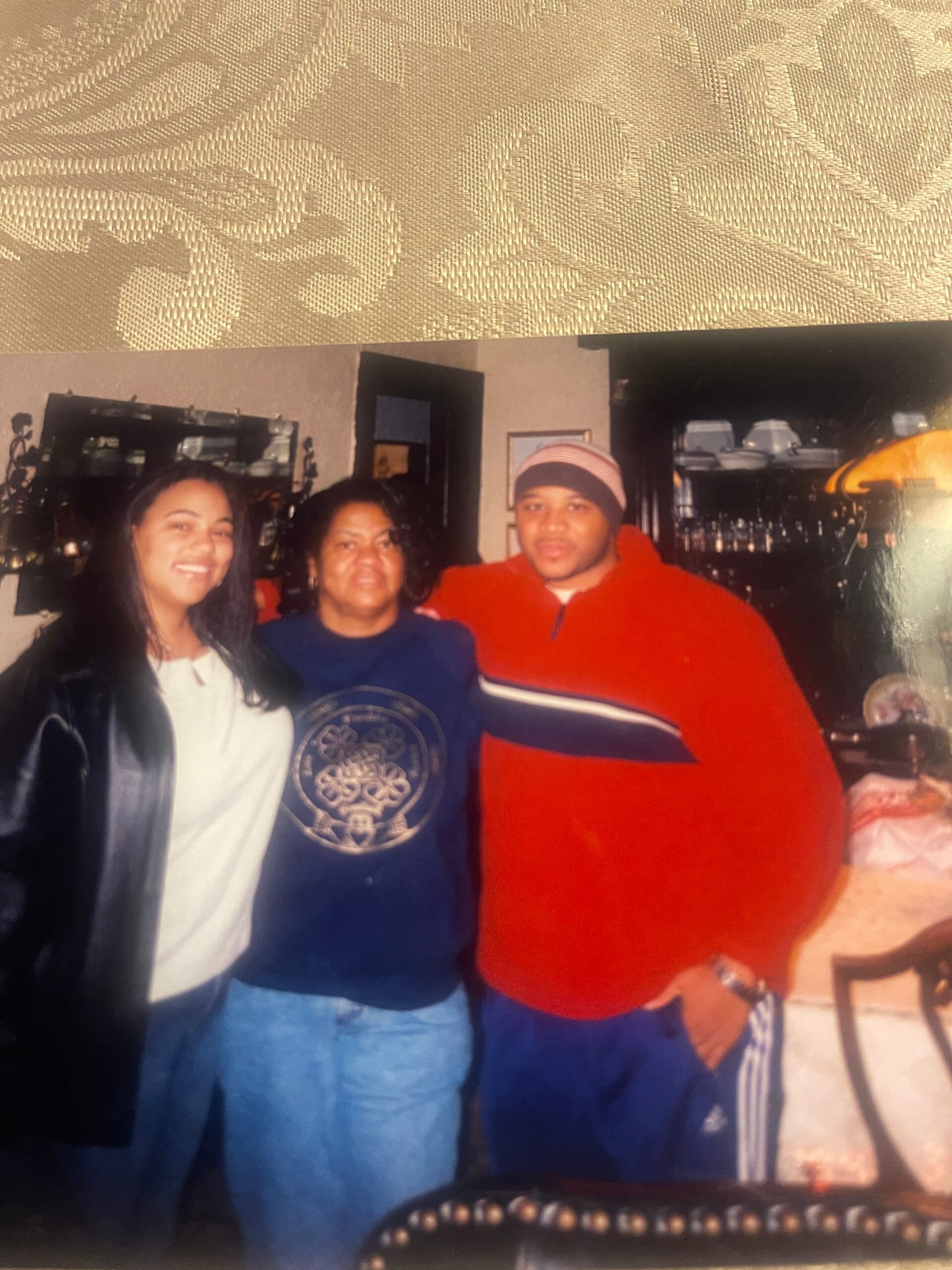 Three people posing together indoors, smiling at the camera.