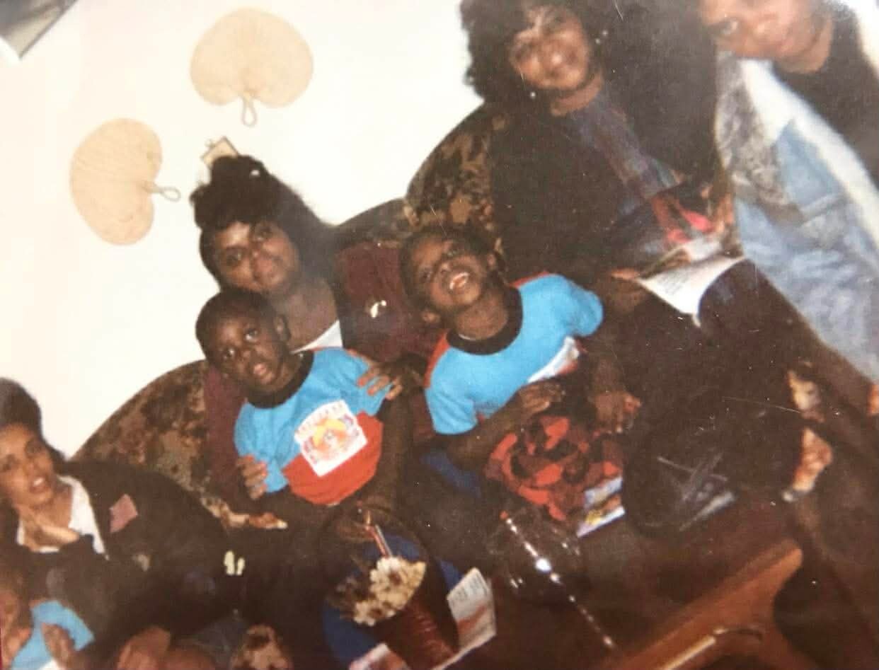 Group of people posing together for a casual photo in a living room during a party or celebration.