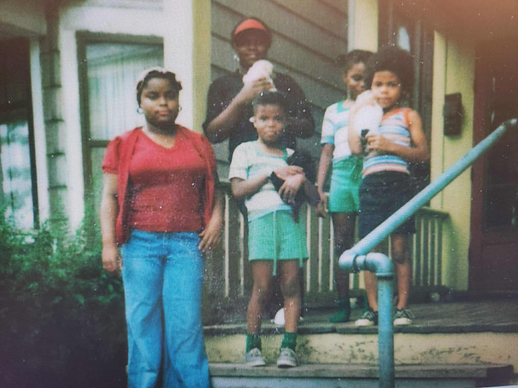 Family group posing on a front porch with adults and children, some holding babies.