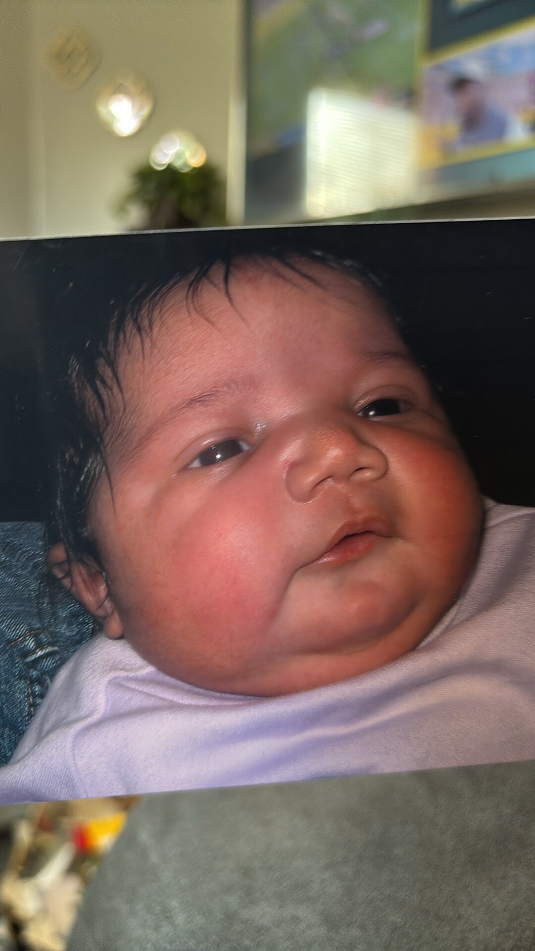 Close-up of a newborn baby with rosy cheeks and dark hair looking to the side.