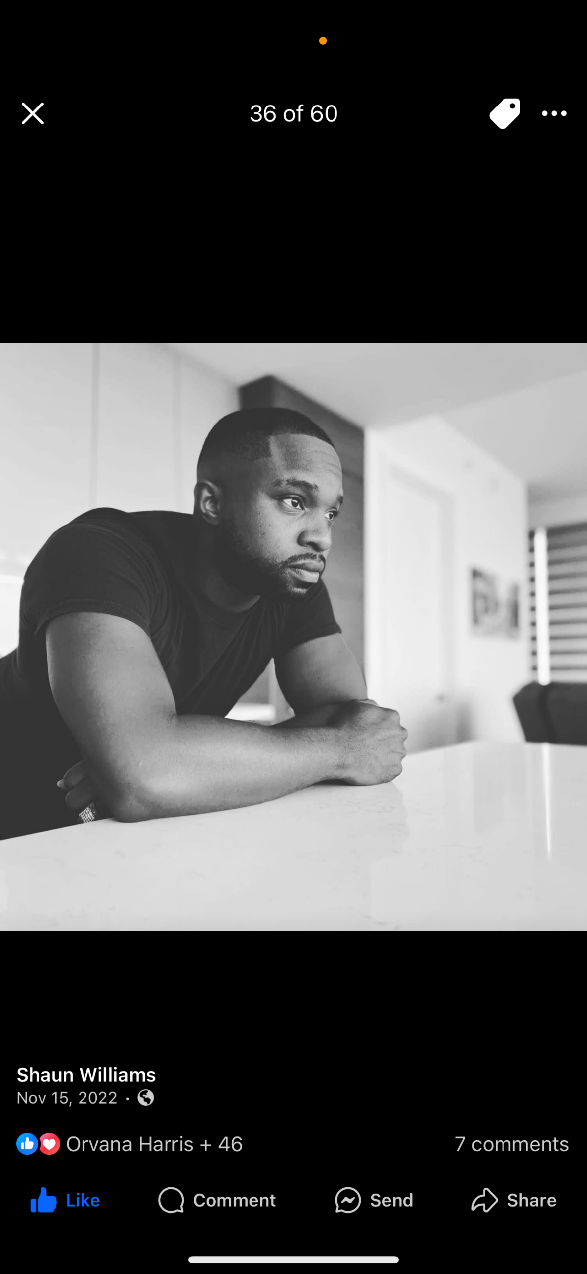 Black-and-white photo of a man leaning on a kitchen counter, looking thoughtful.
