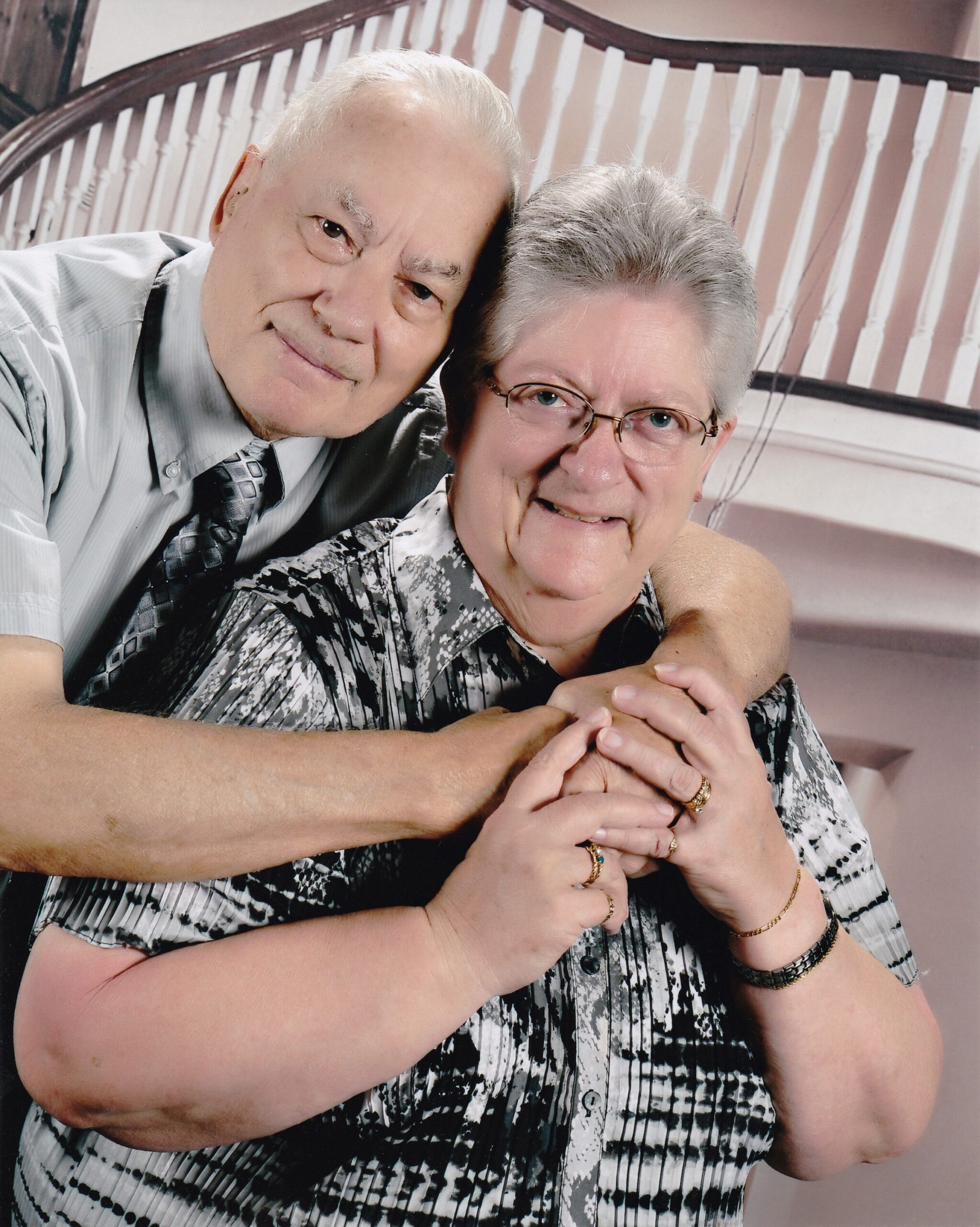 Older couple smiling and embracing for a selfie, close‑up portrait in a home setting.