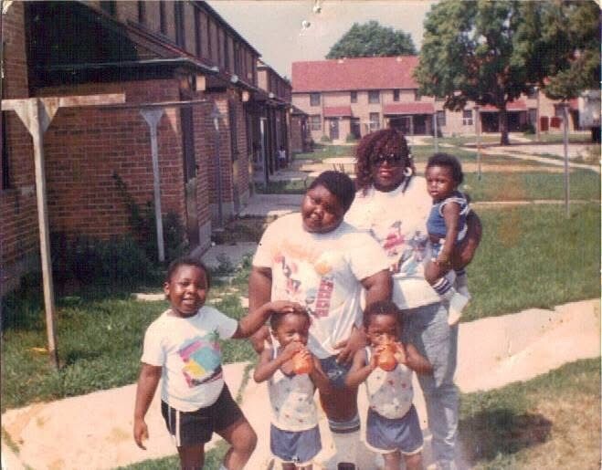 African American family posing on a sidewalk in a suburban neighborhood.”
