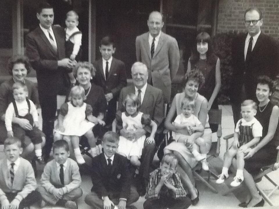 Black-and-white multigenerational family photo posing on a porch with children in front.