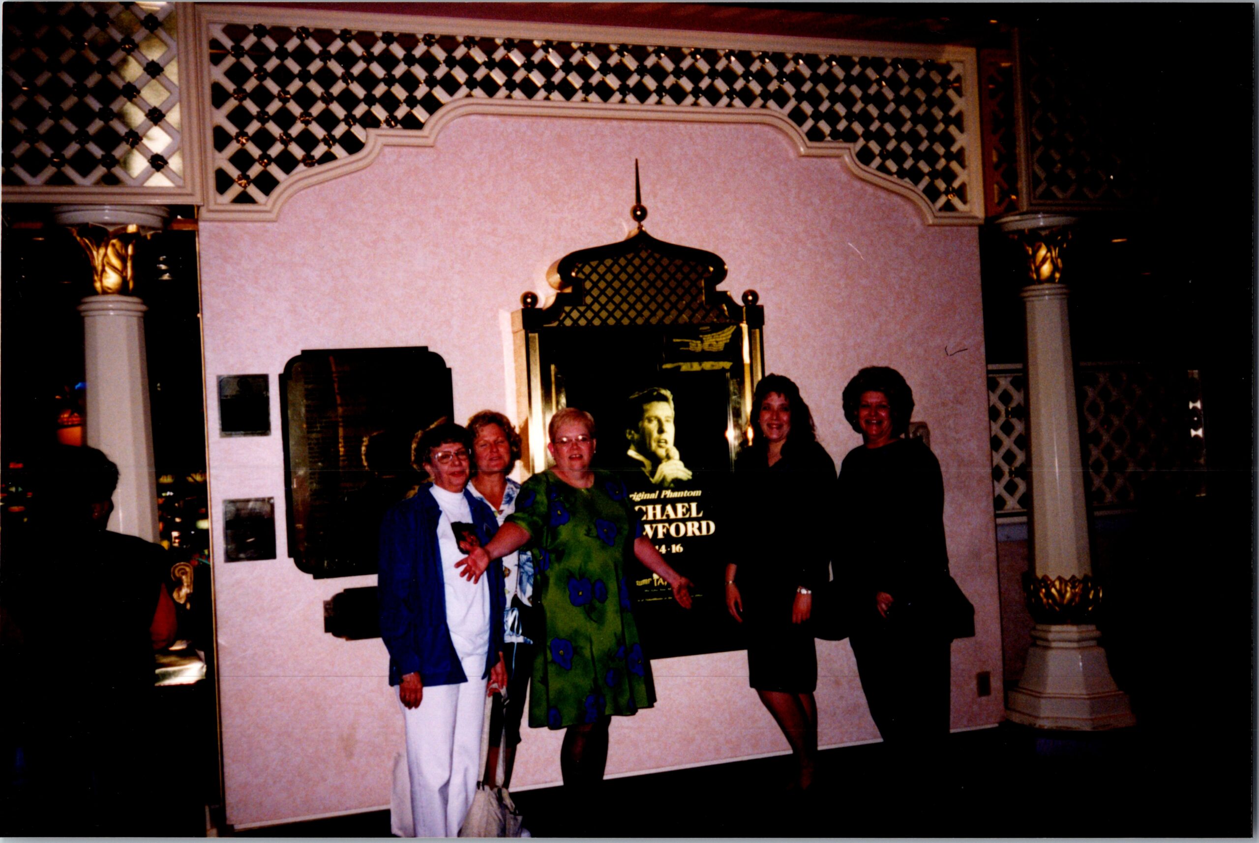 Group of women posing for a photo in a fancy lobby with decorative lattice panels, columns, and a tall ornate mirror behind them.