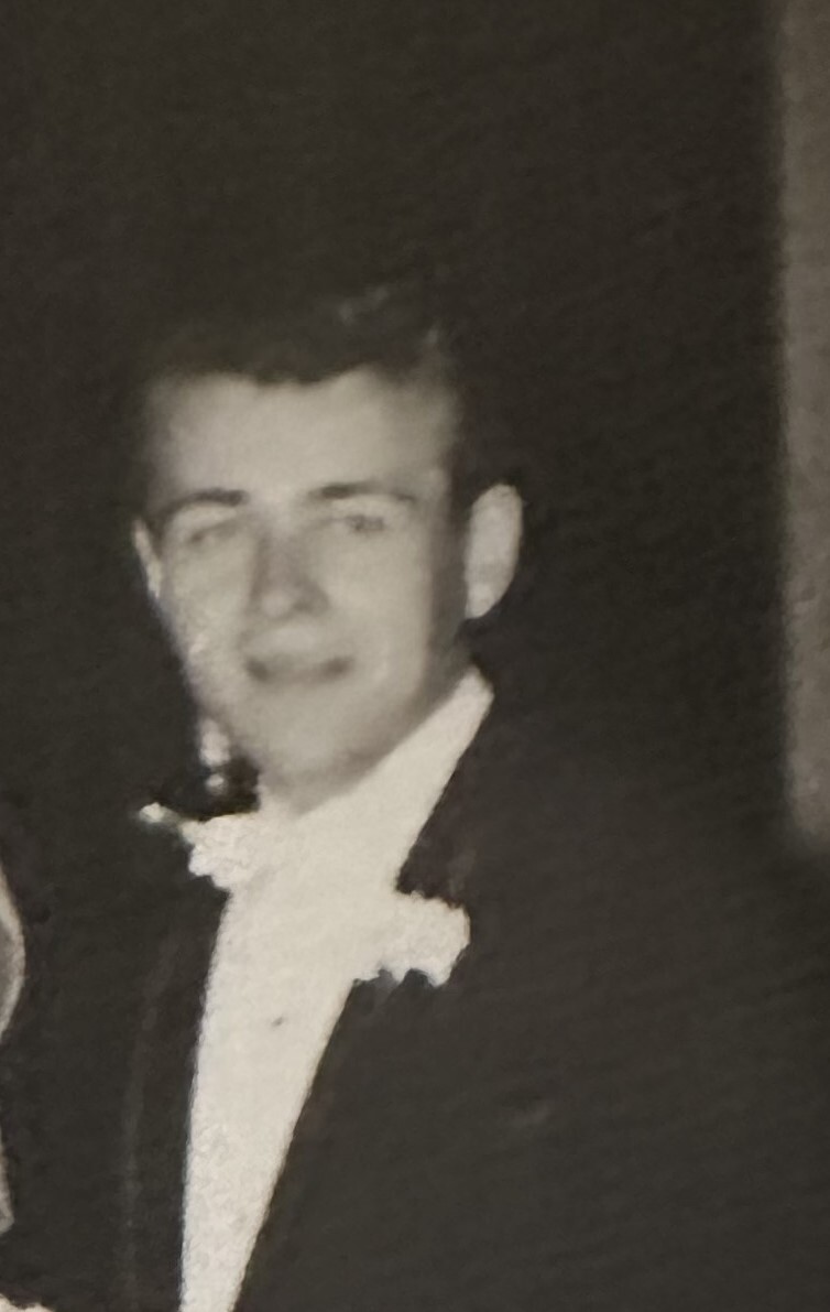 Man in a tuxedo and bow tie, smiling for a formal portrait (black-and-white photo).