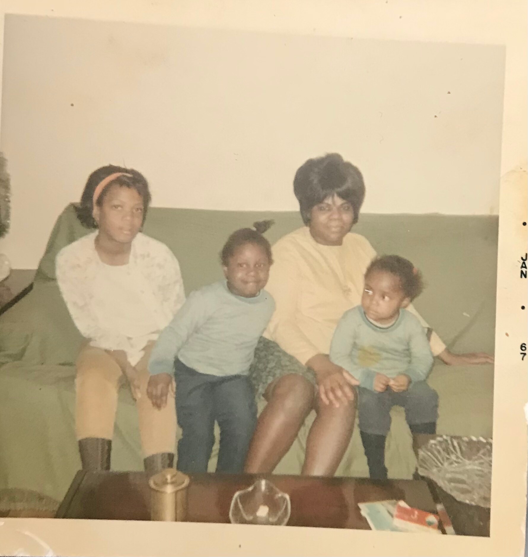 A family of five posing on a sofa in a living room: two adults with three children in a casual portrait.