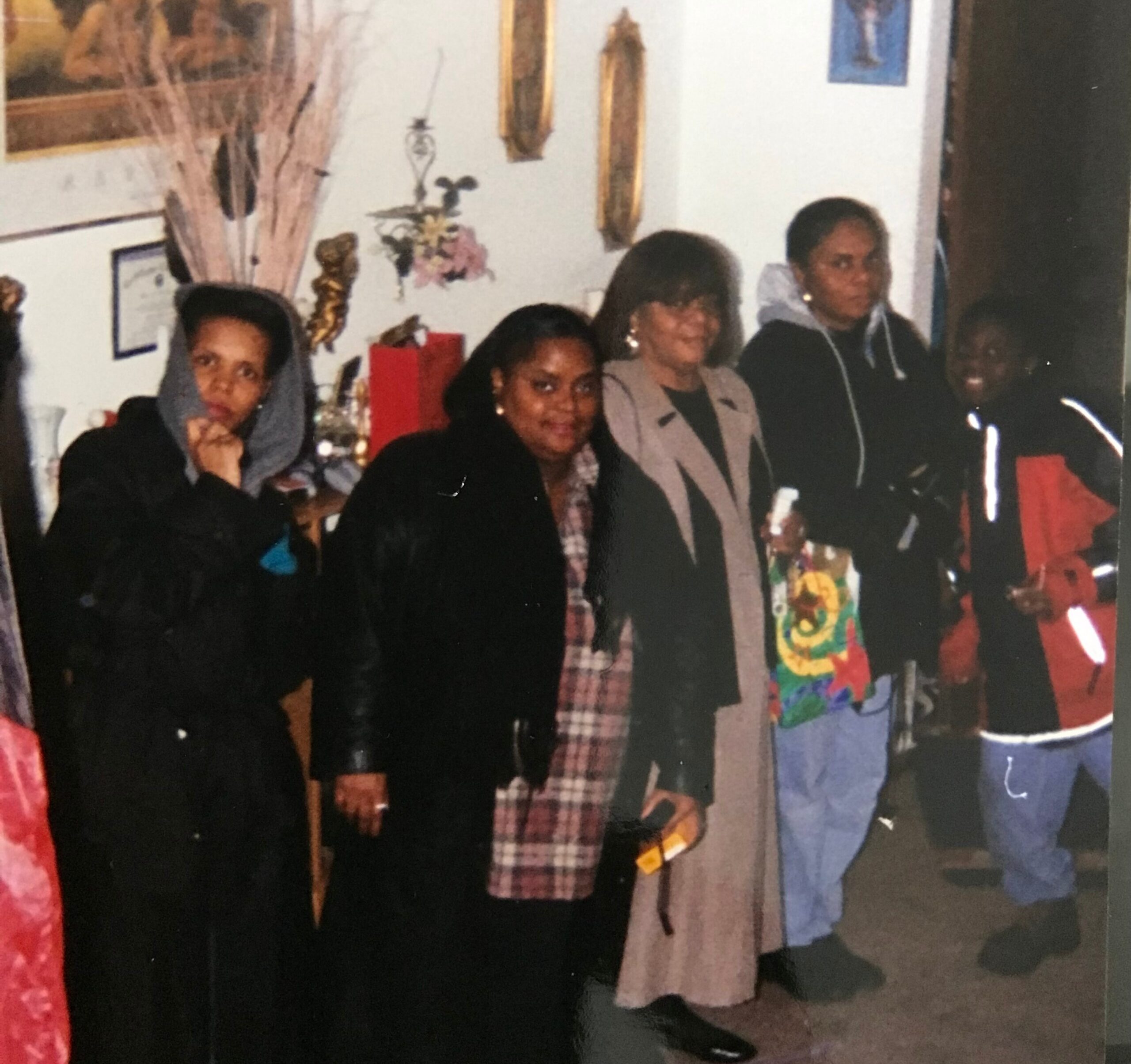 Group of people posing together indoors at a social gathering, with decorations on the wall behind them.