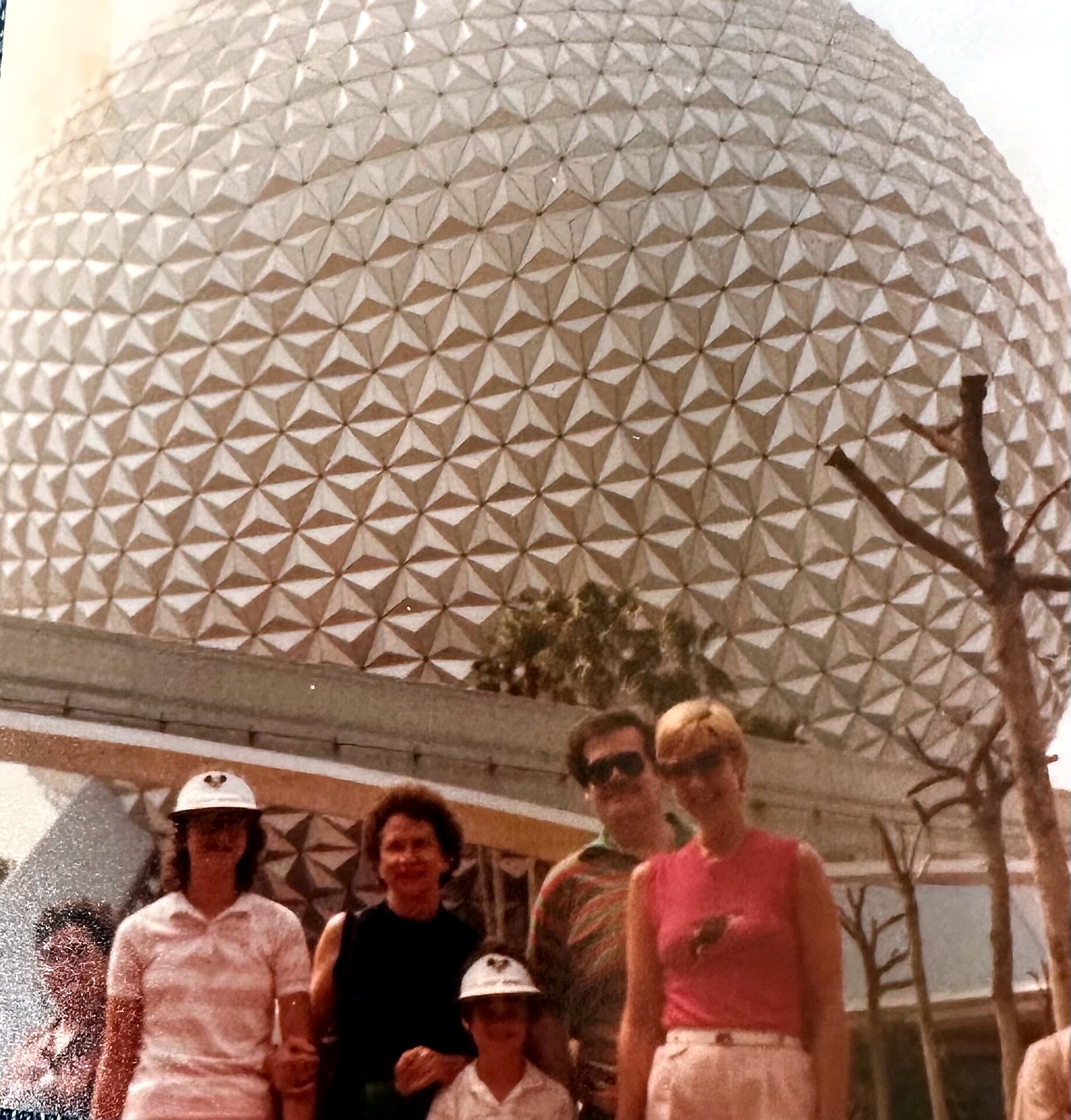 Group of people posing for a photo in front of the geodesic Spaceship Earth dome at Epcot.