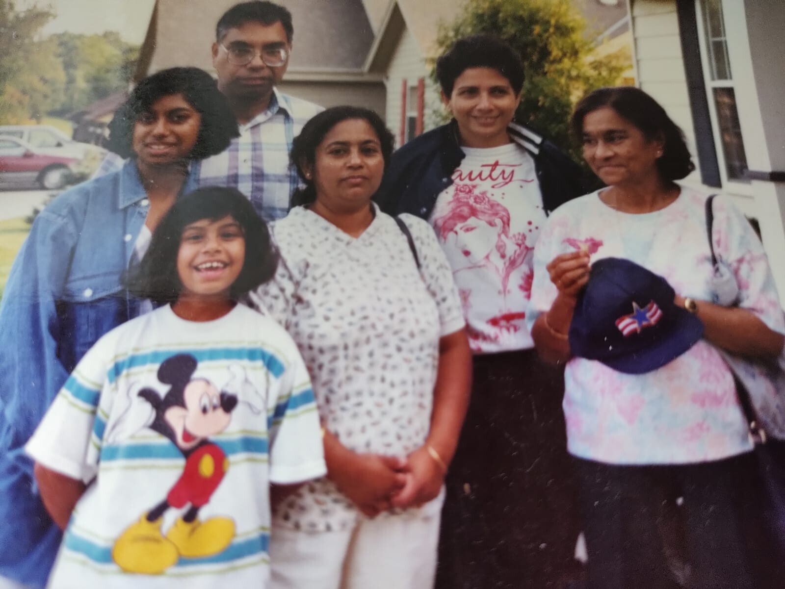 Six family members pose outdoors for a group portrait, smiling and standing together in casual clothes.