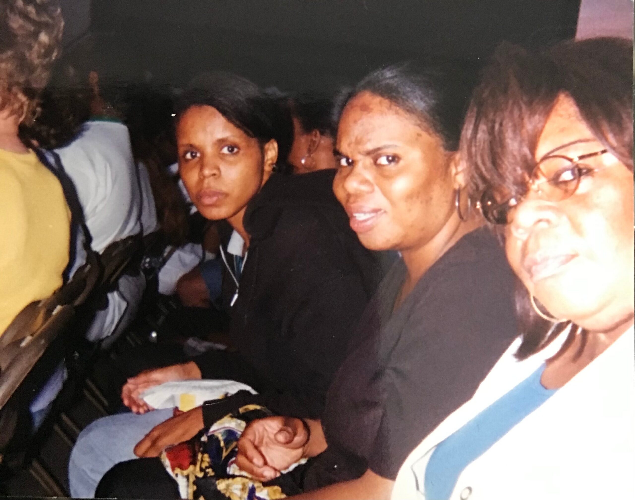 People posing together at a social gathering, with a woman in a black top looking toward the camera in the center.