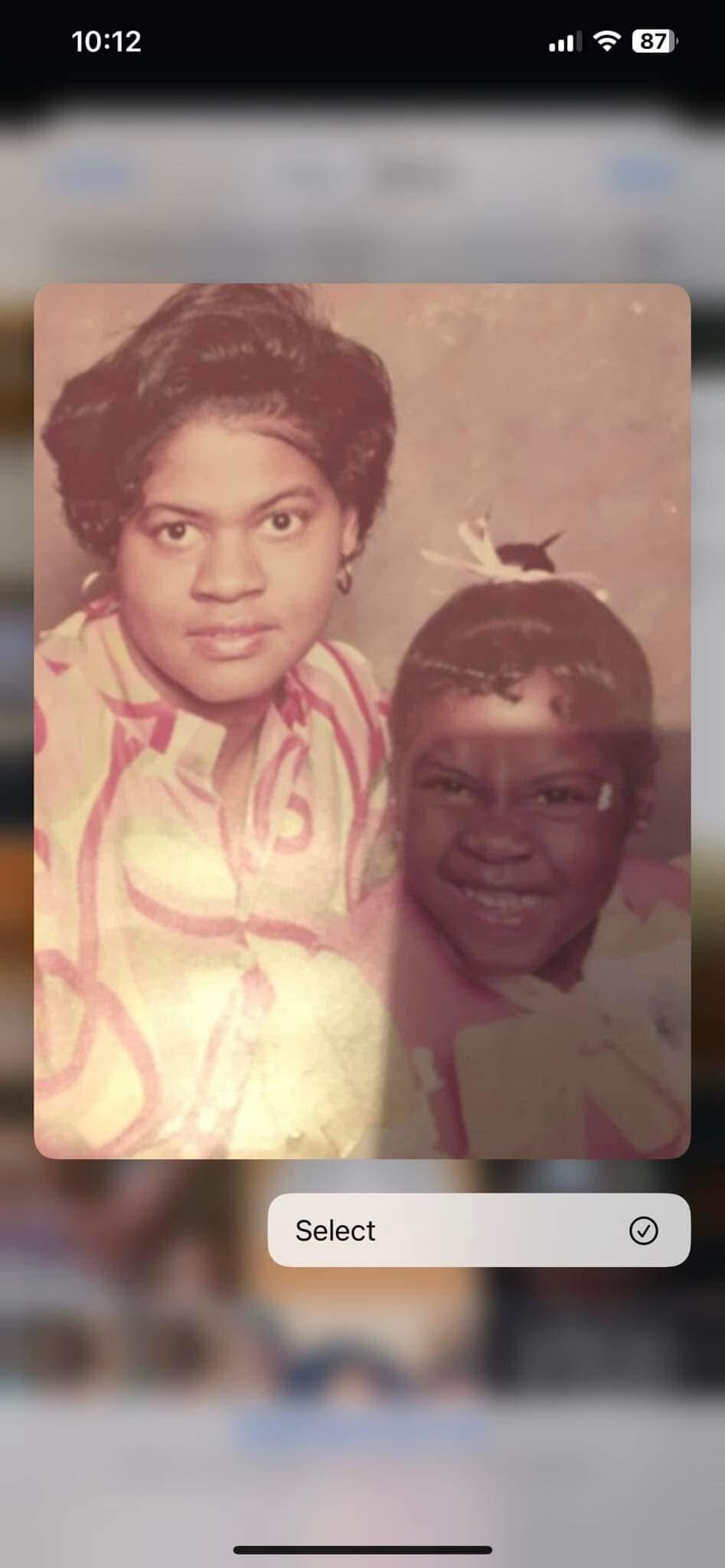 Two smiling people in a vintage photo: a woman on the left and a young girl on the right, both looking at the camera.