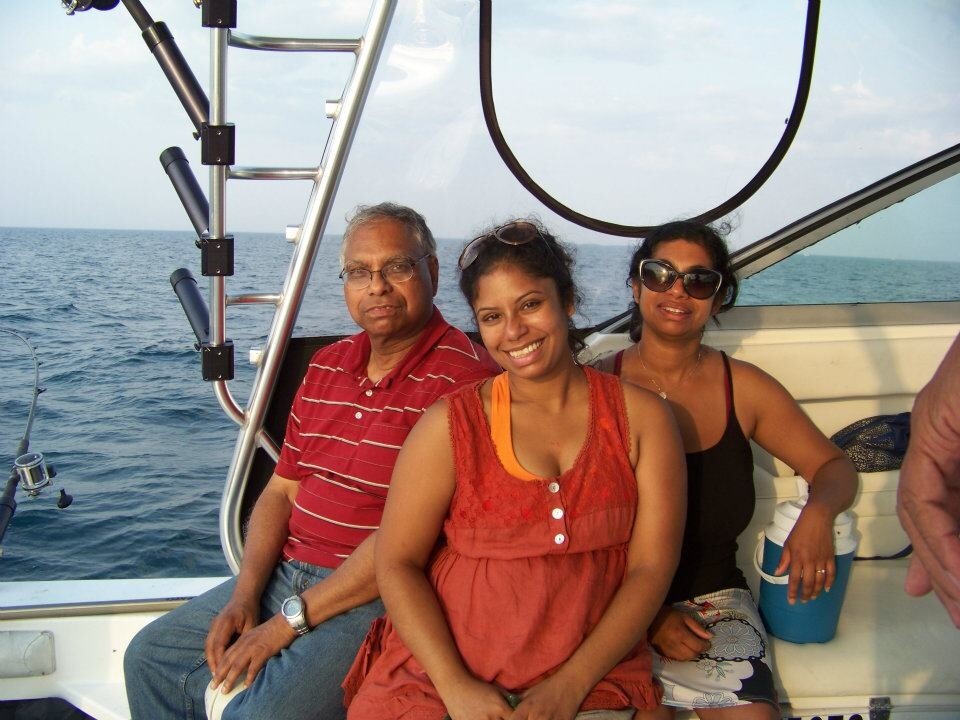 Three adults lounging on a boat deck with the sea behind them, smiling at the camera.