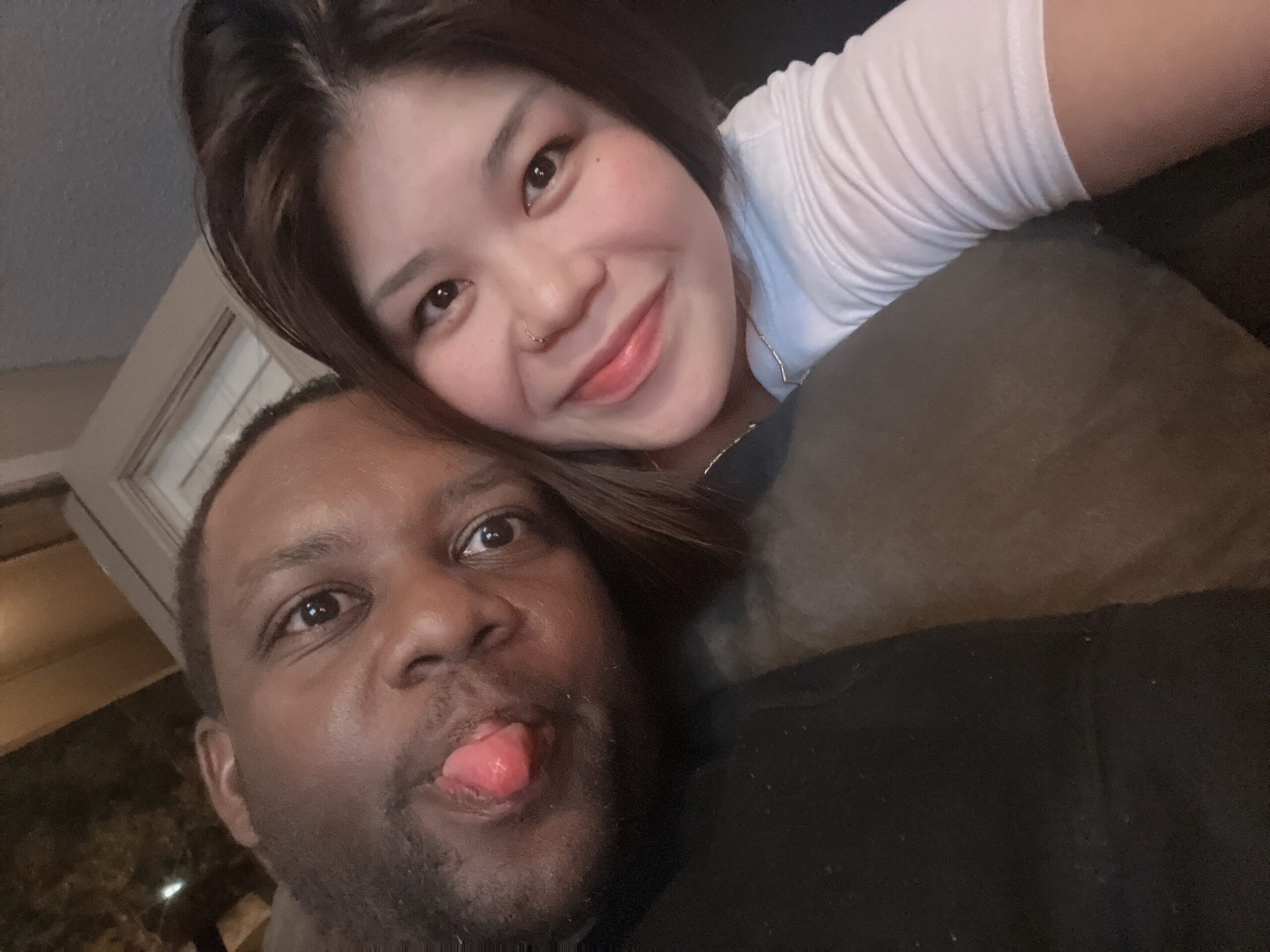 Two friends posing closely for a selfie, one sticking out her tongue playfully at the camera.