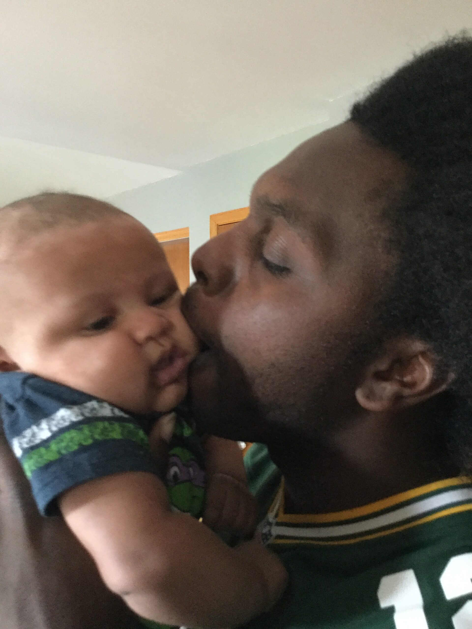 Close-up of a man kissing a baby on the cheek, a tender moment of affection.