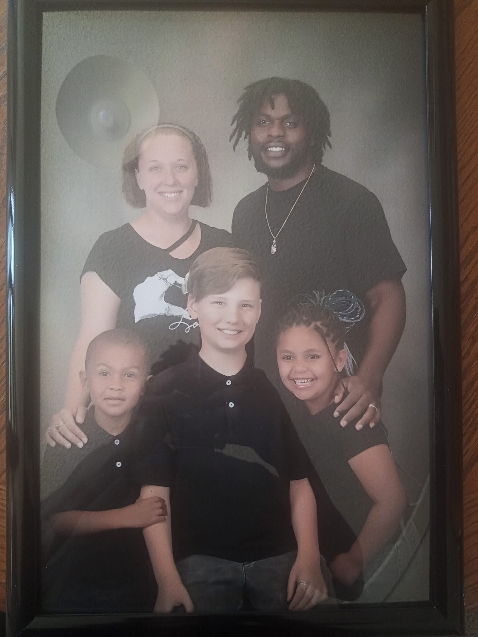 Smiling family of five posing for a studio portrait, with two adults in back and three children in front.