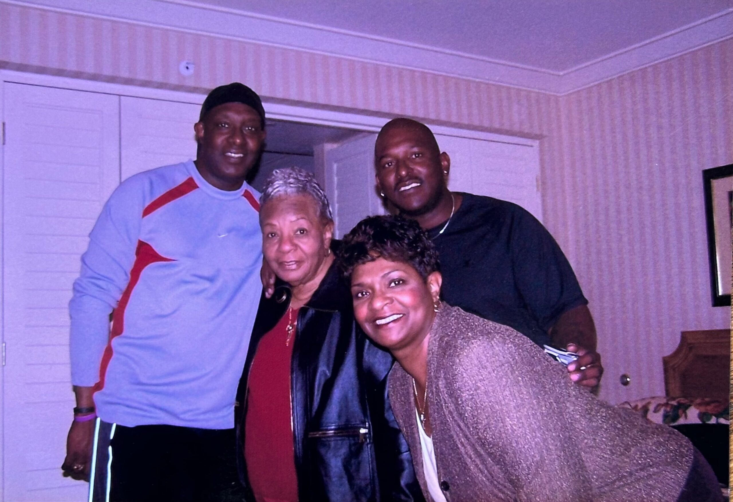 Four people posing together indoors, smiling for a family photo?