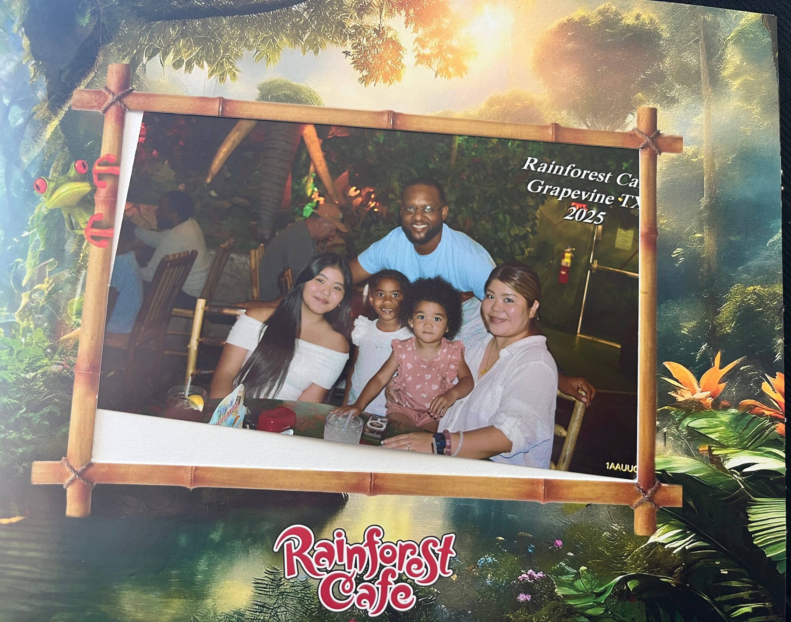 Family portrait at Rainbow Forest Cafe: adults and children sit at a table in a rainforest-themed restaurant, smiling at the camera.”] }{