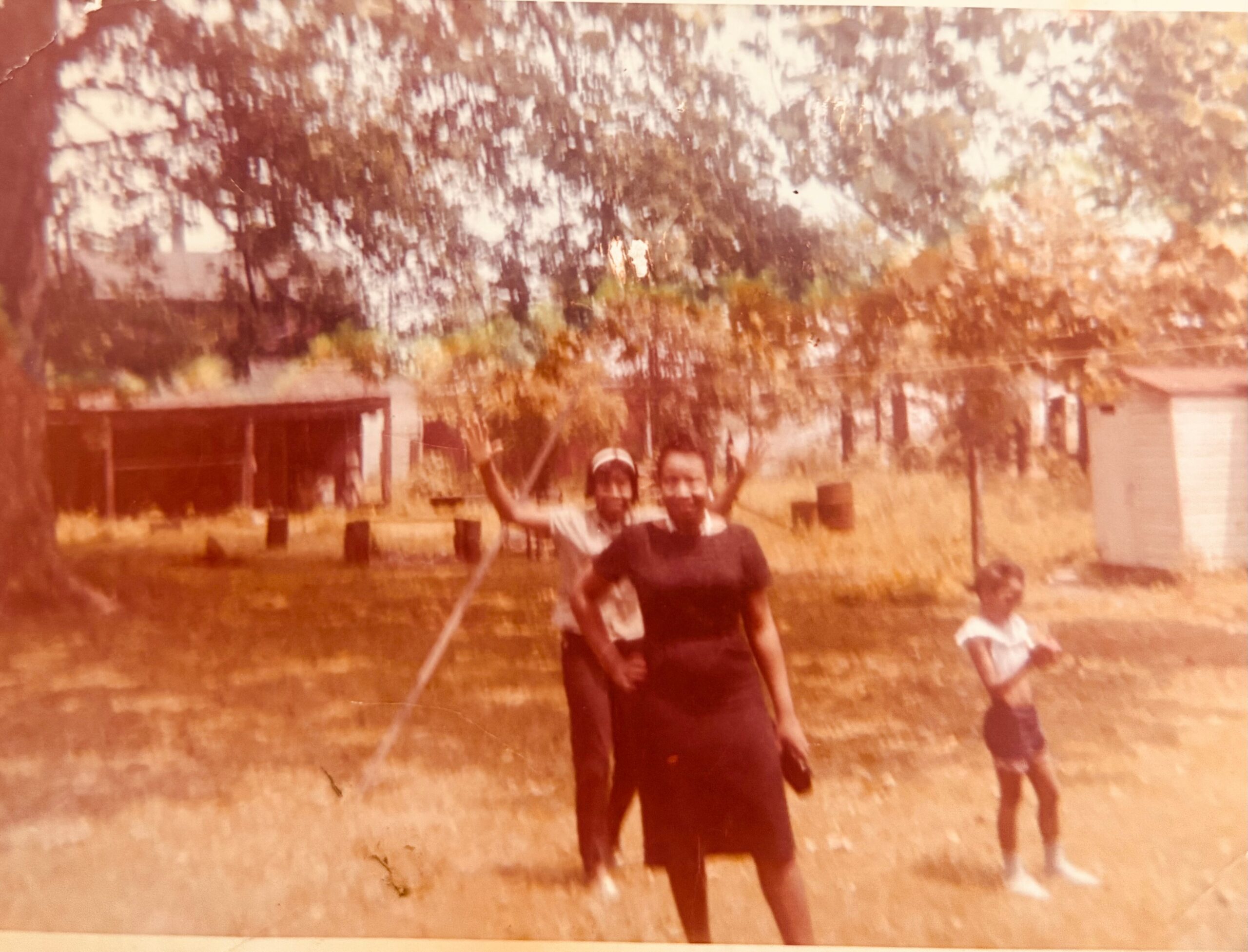 Two people wearing masks stand in a yard outdoors, with trees and a house in the background (motion blur).