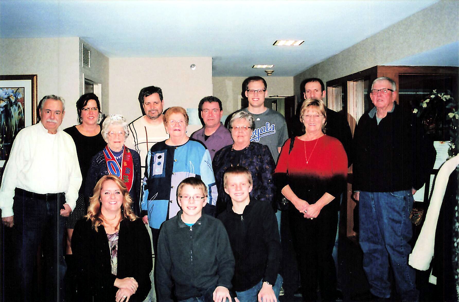 Large family group photo in a living room, with adults standing behind two smiling boys in front.