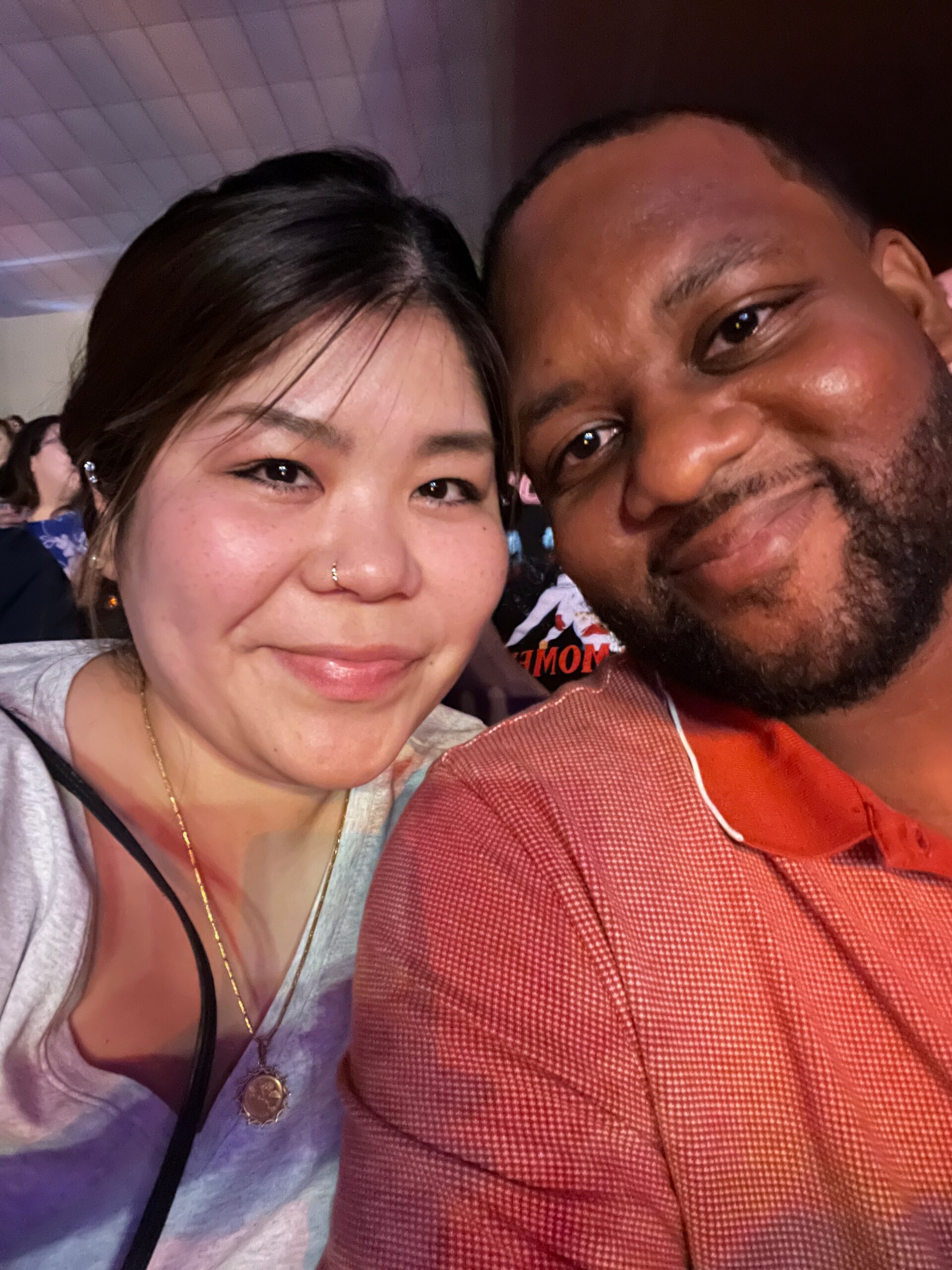 Close-up selfie of a smiling woman with a nose ring and a man with a beard beside her at an event.科技