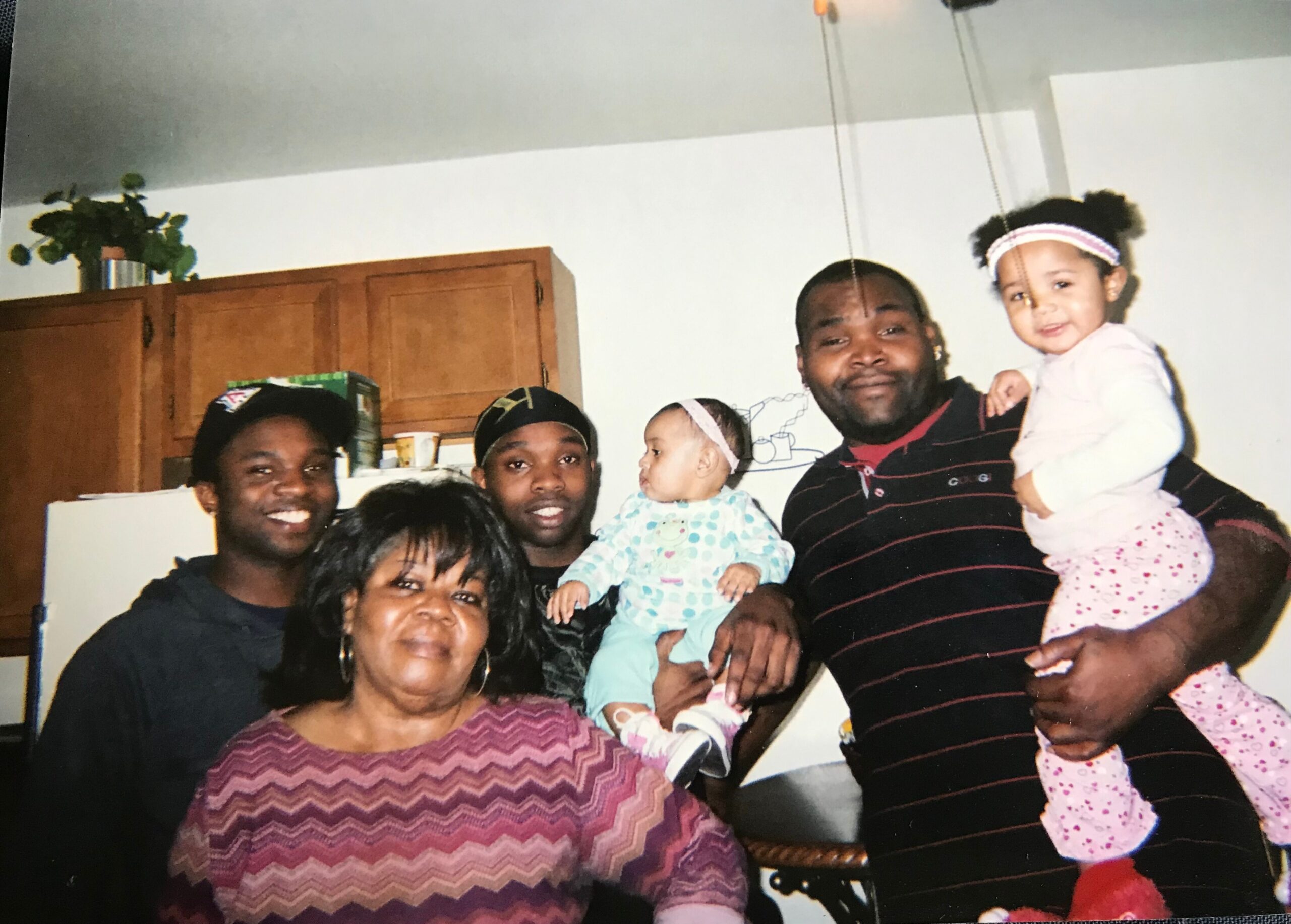 A crowded family group posing in a kitchen, adults and several children smiling at the camera.