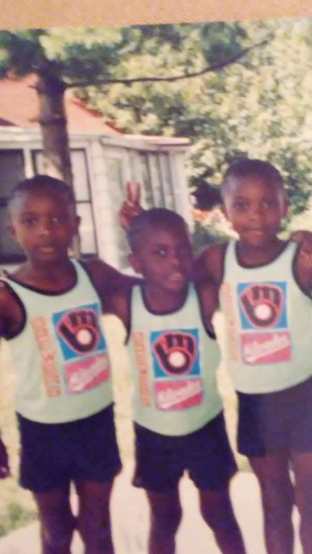 Three young boys in mint-green sports jerseys posing together outdoors for a photo.