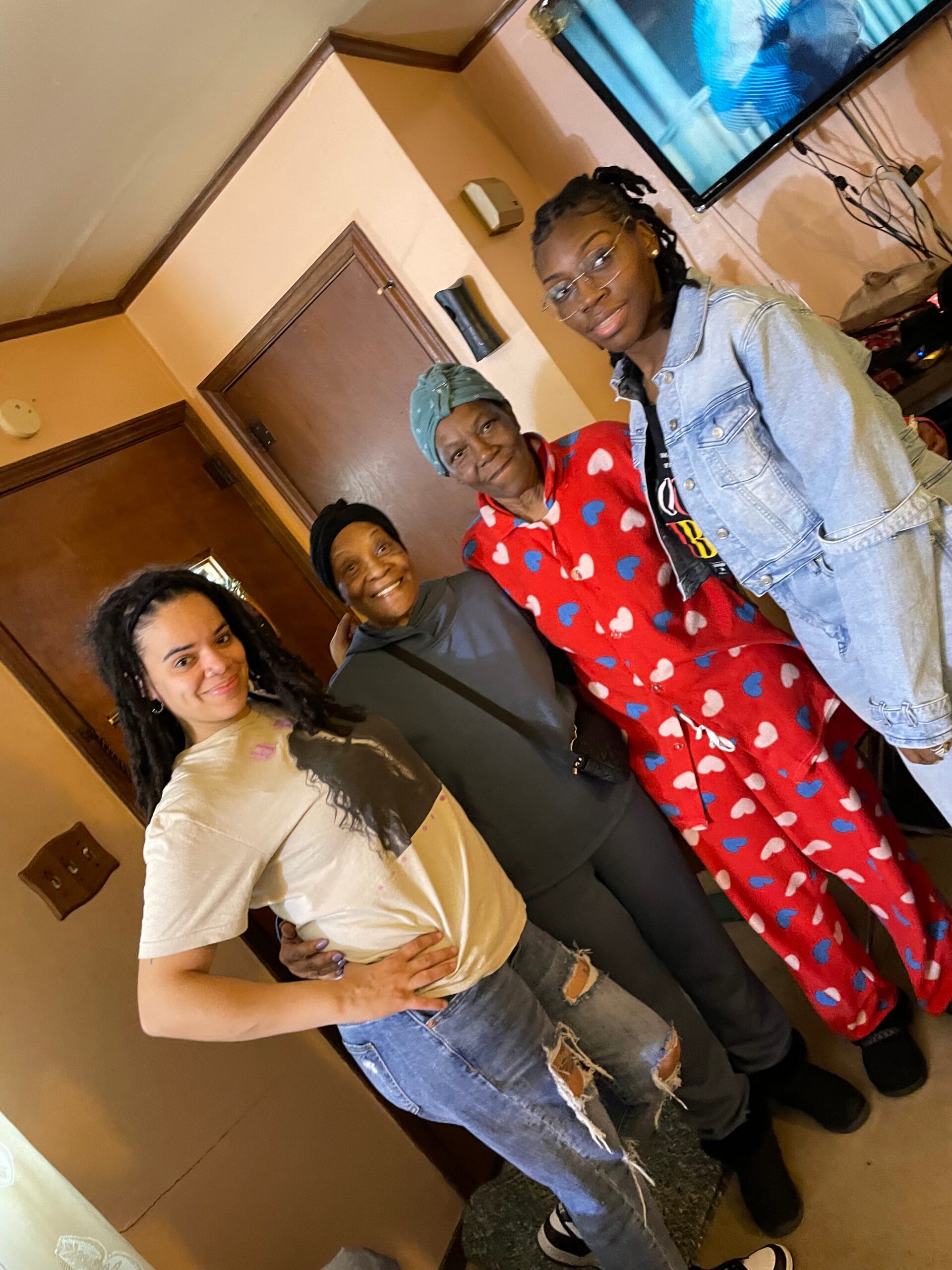 Four women in a hallway posing for a photo, smiling at the camera.