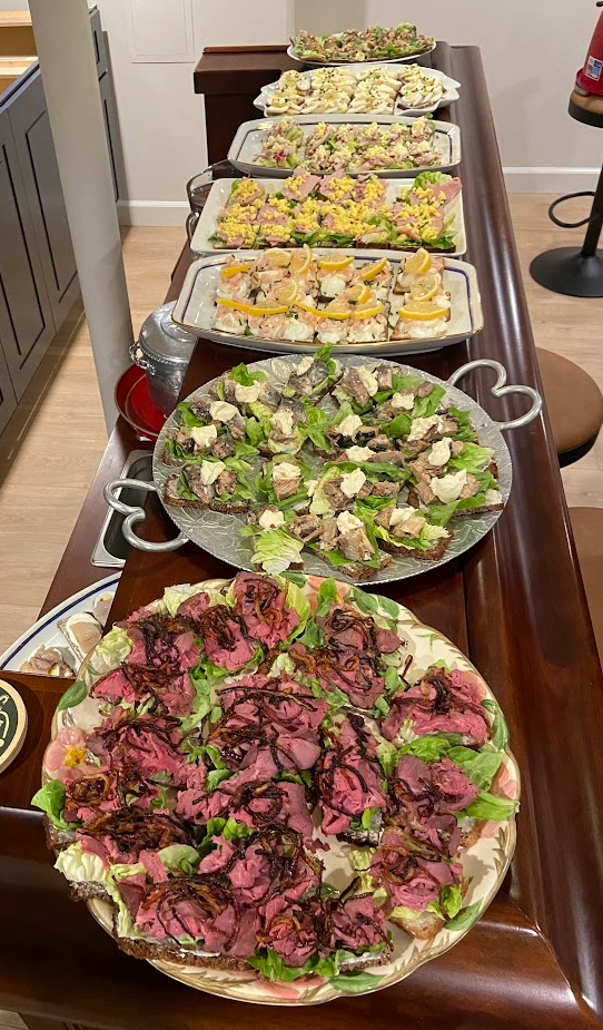 Long buffet table with multiple platters of hors d'oeuvres and finger foods, arranged in rows for a party or gathering, viewed from above at an angle.