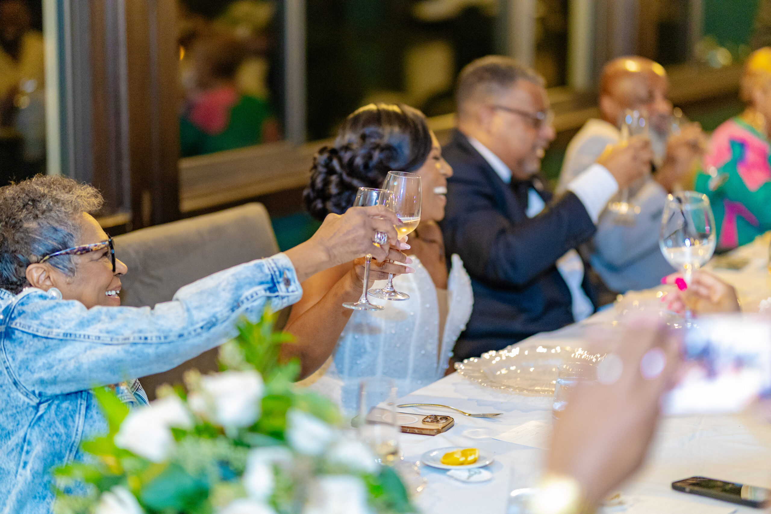 Group of people at a long dinner table raising wine glasses in a toast.