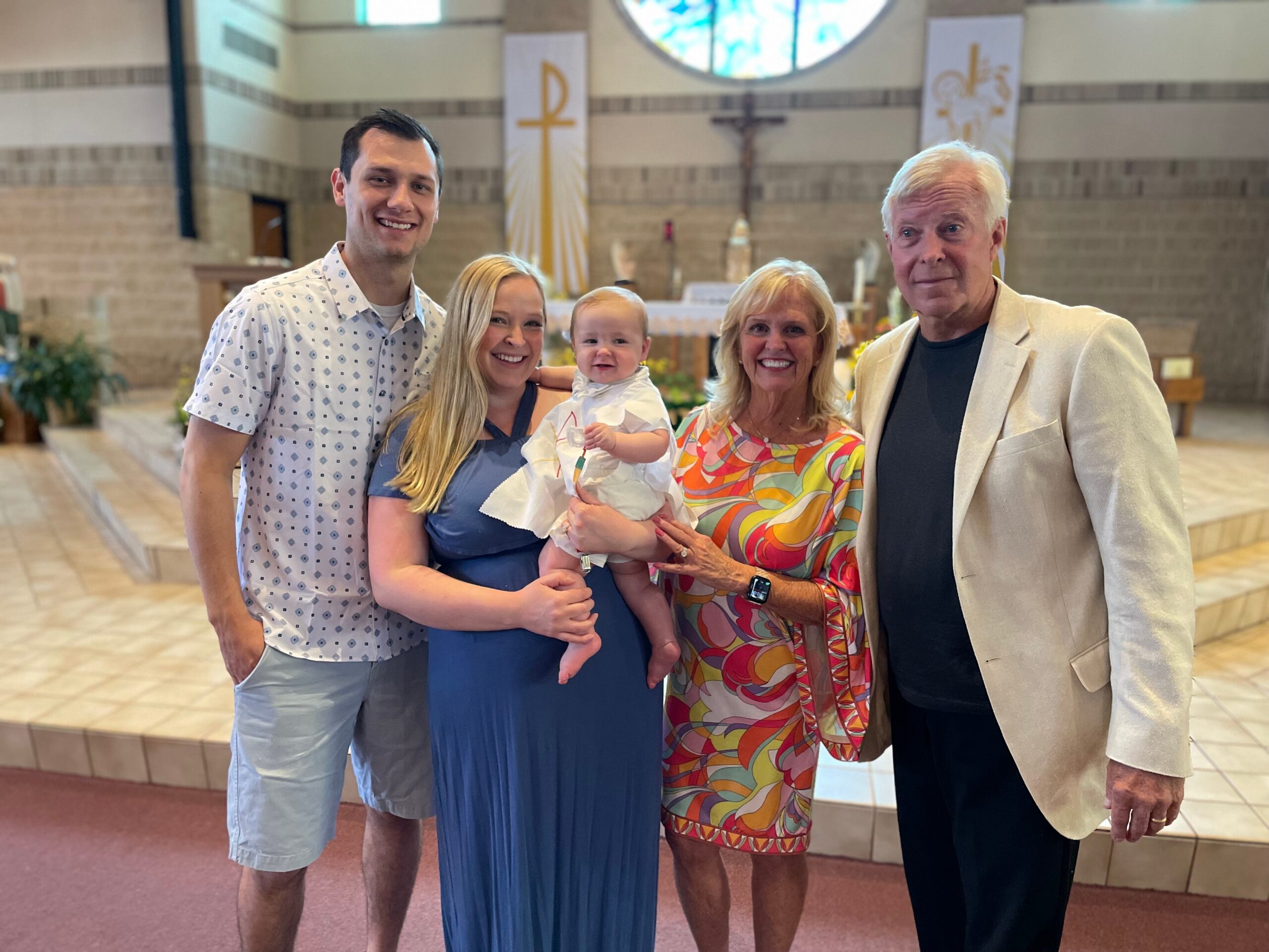 Smiling family posing with a baby in a church sanctuary.