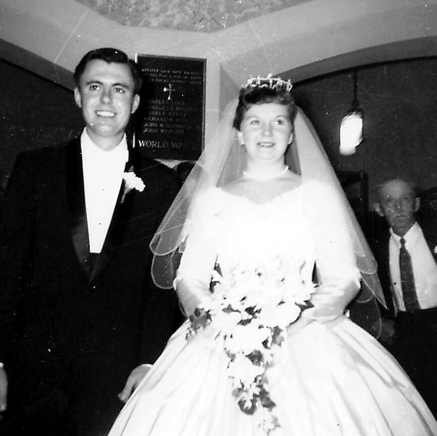 Bride and groom walking down the aisle after the wedding, bride in a full gown with veil and bouquet, groom in a tuxedo.