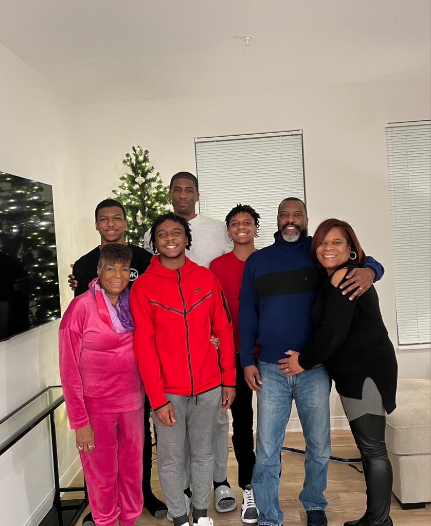 A multi-generational family posing together in a living room with a Christmas tree in the background.