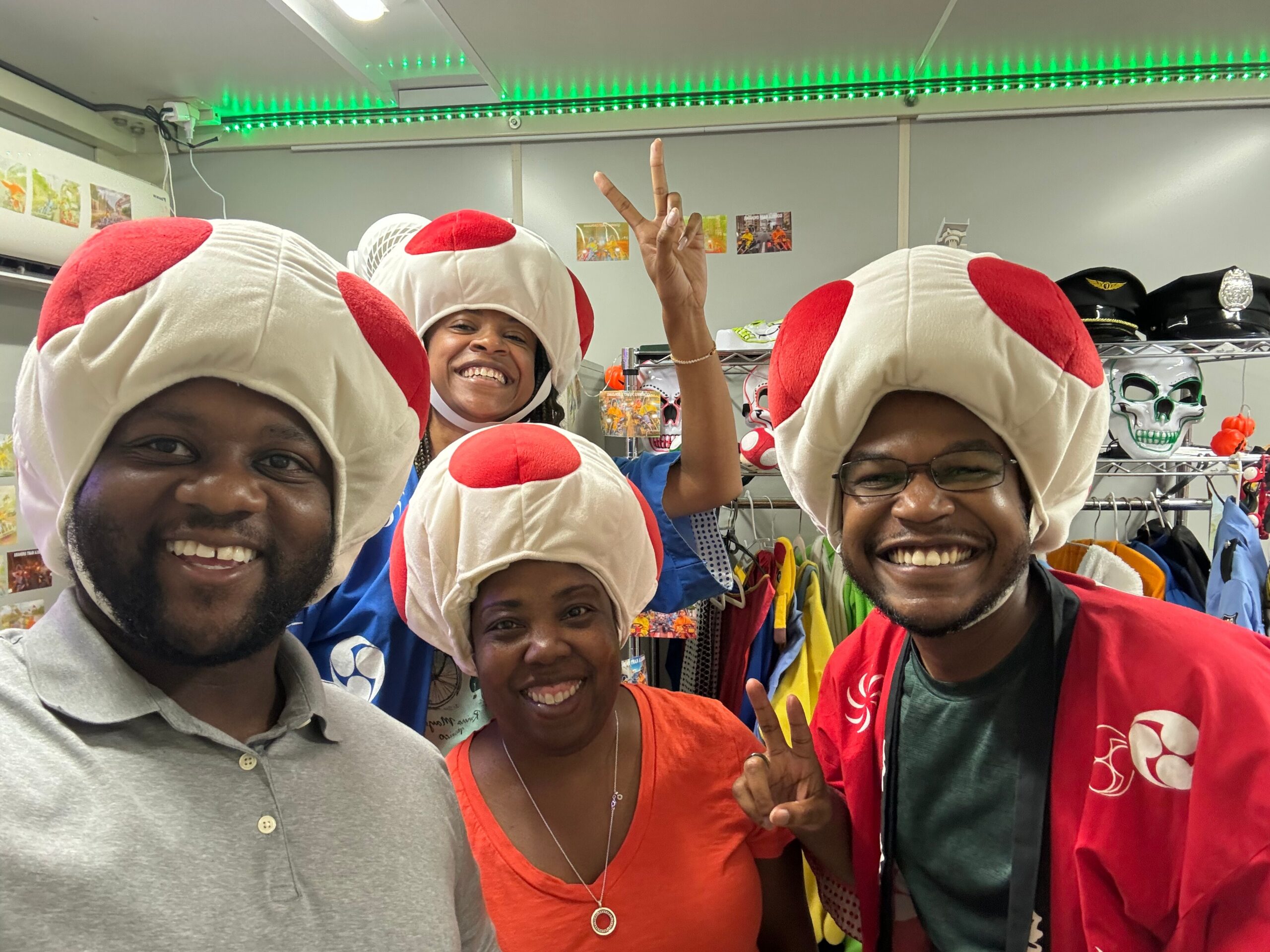 Group of smiling people wearing oversized white and red mushroom hats in a store.