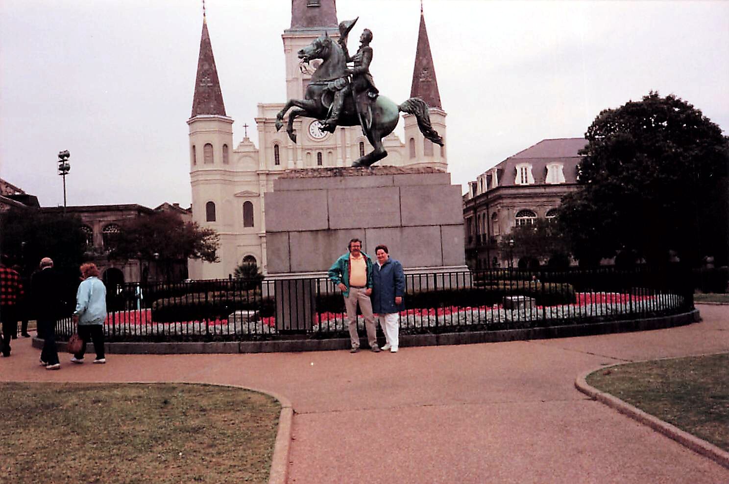 Two people pose beside the equestrian statue of Andrew Jackson in Jackson Square, New Orleans, with St. Louis Cathedral in the background.