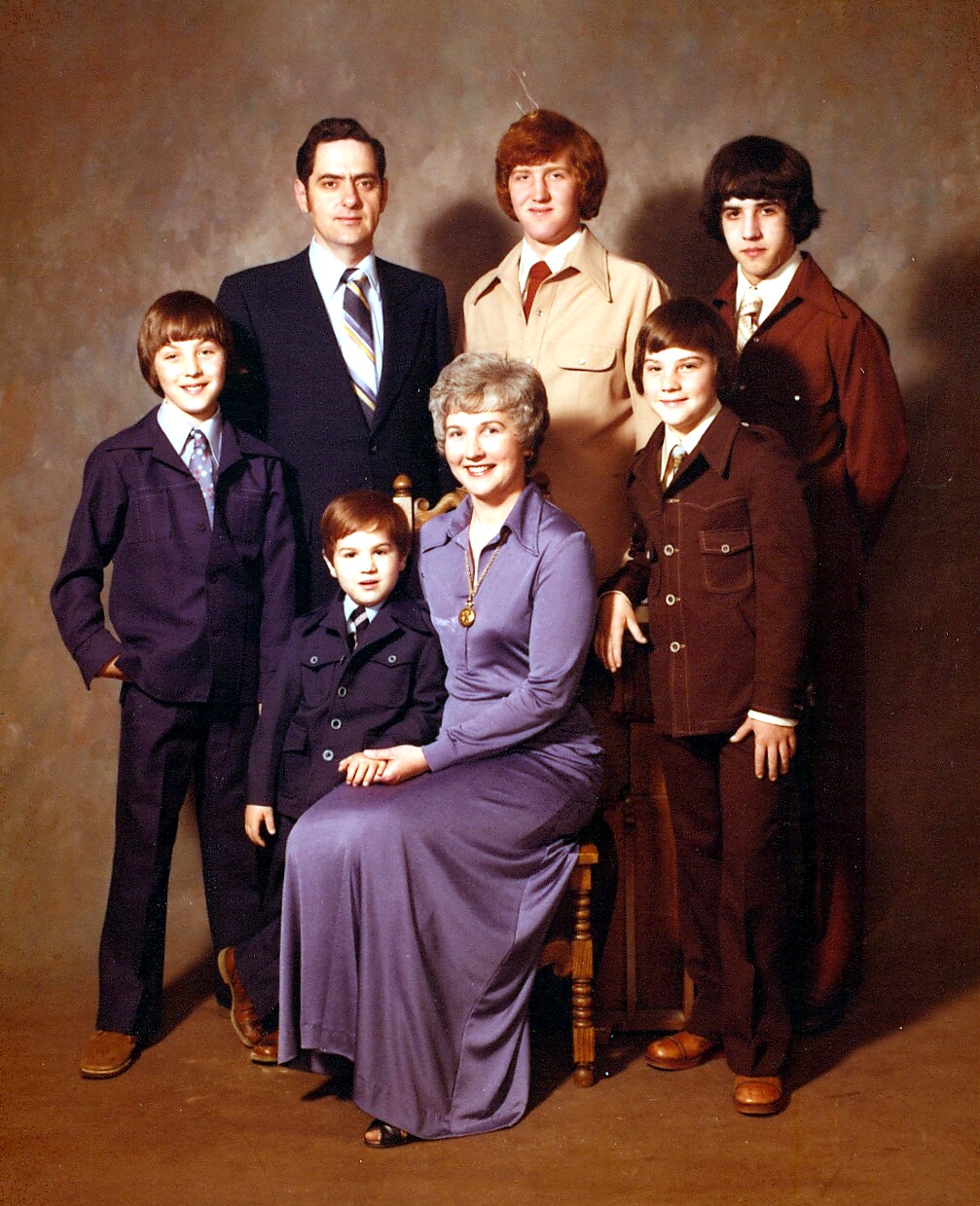 Family portrait: father in a suit, mother seated in a lavender dress with her youngest son on her lap, and four sons standing around. (1960s studio photo)