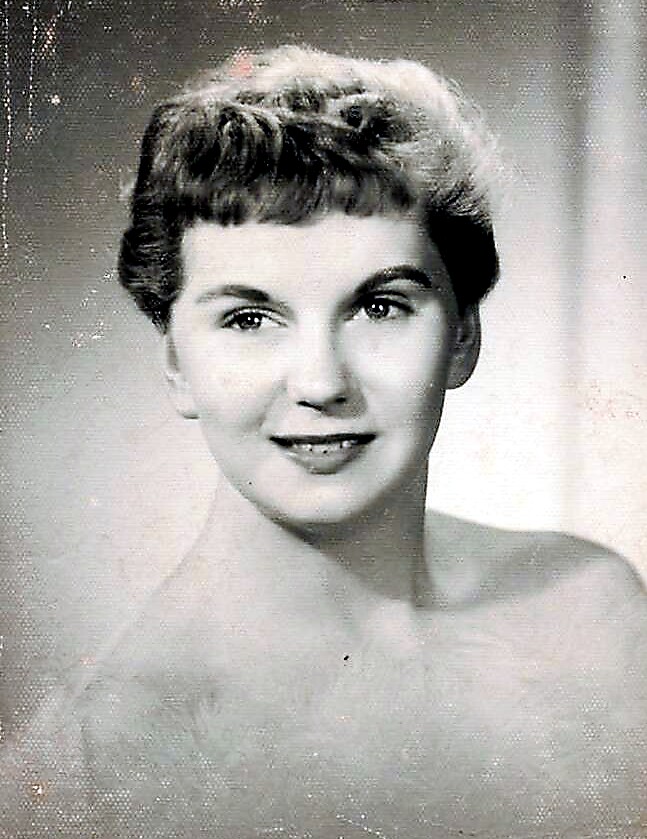 Vintage black-and-white studio portrait of a smiling young woman with short curled hair and bare shoulders.