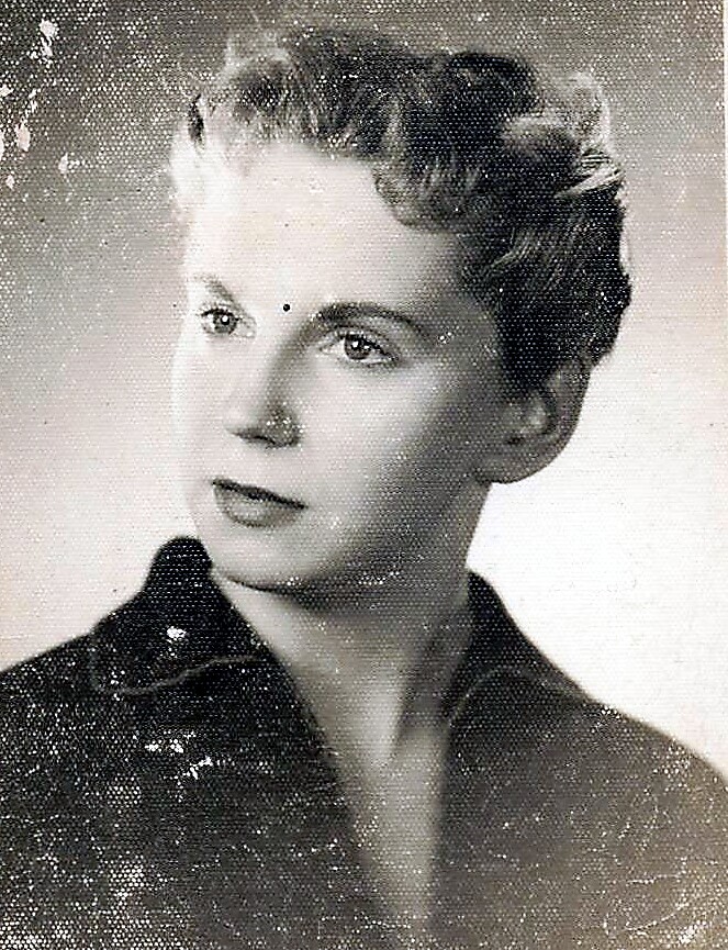 Vintage black-and-white portrait of a woman with short, wavy hair looking slightly to the left, wearing a dark collared blouse.