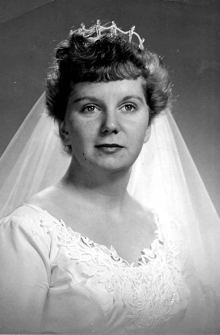 Bride wearing a lace wedding gown with veil and tiara, posing for a studio portrait.