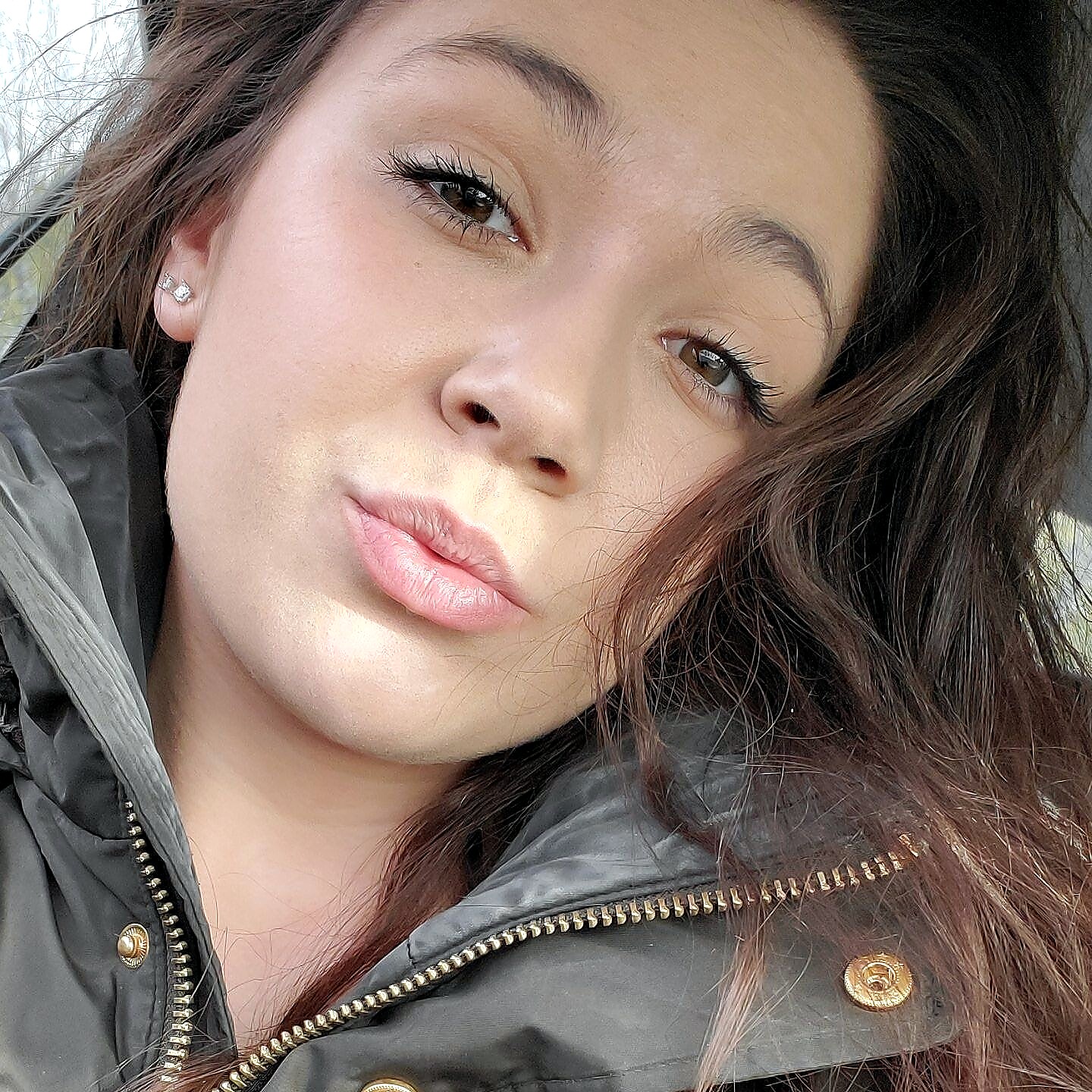 Close-up portrait of a young woman with dark hair wearing a green jacket, looking slightly to the side, lips slightly parted.