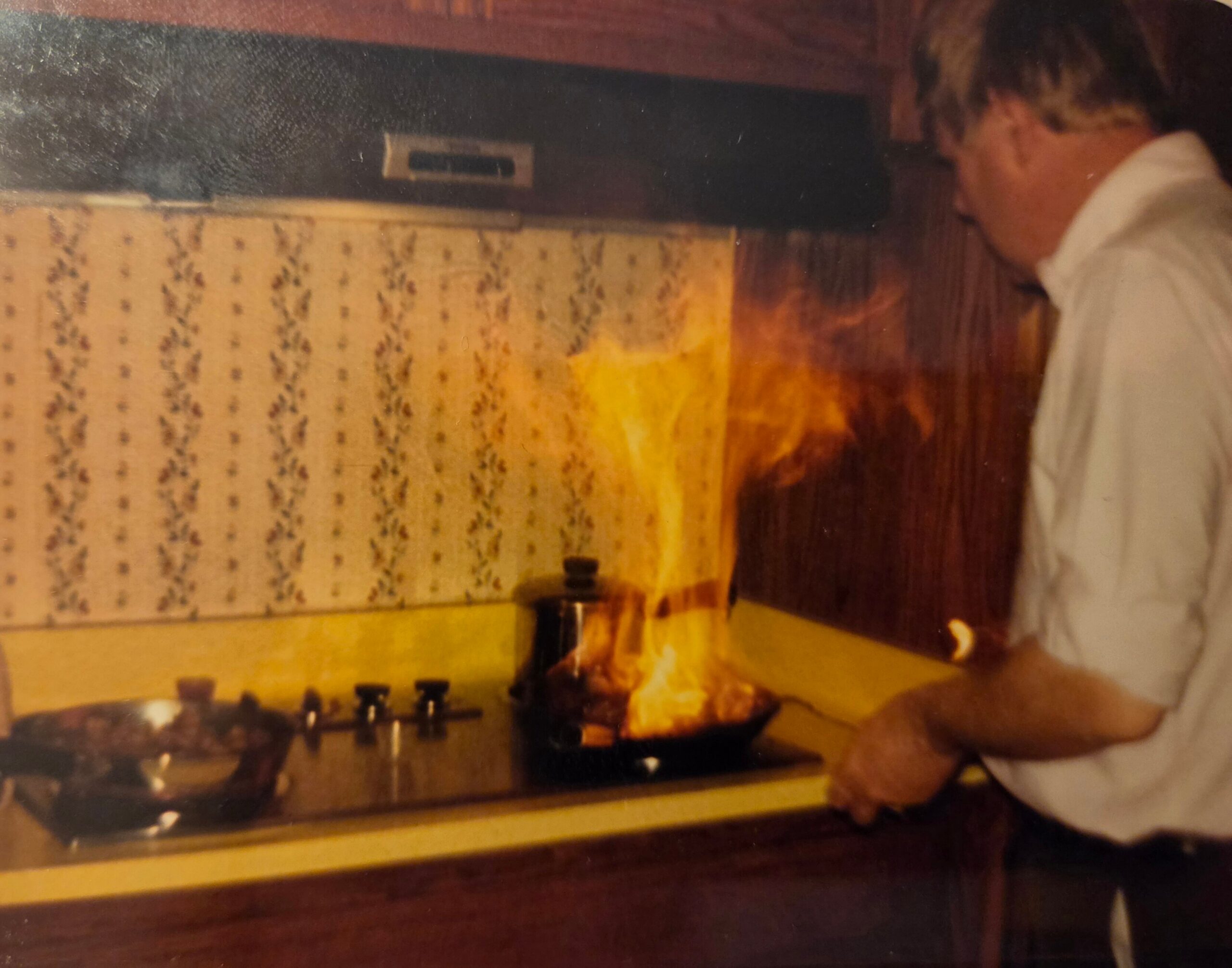 Person in a white shirt leaning toward a gas stove with a roasted turkey on the front burner in a retro-style kitchen