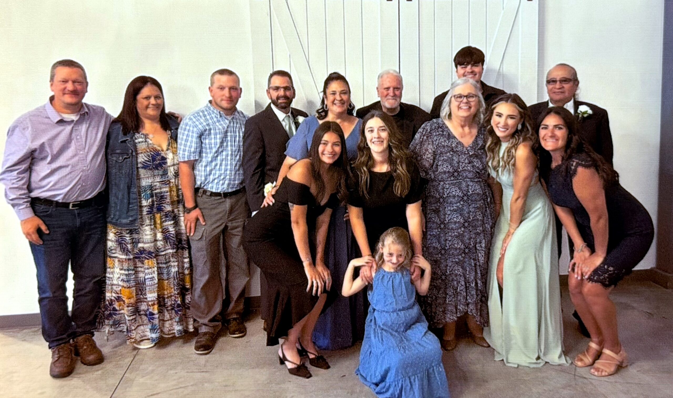 A large group of people in formal and semi-formal attire posing together indoors for a photo.