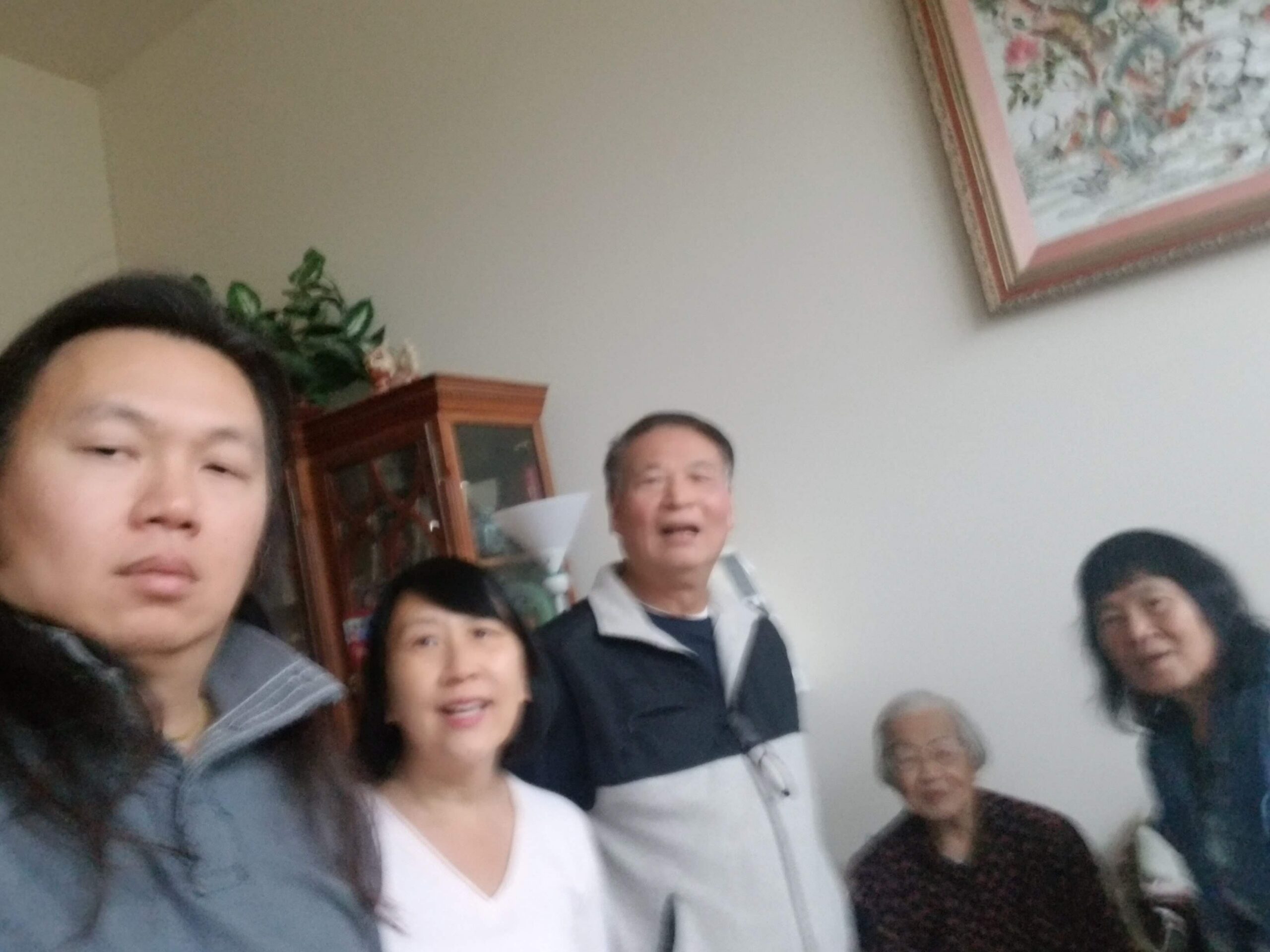 Group selfie of several adults gathered in a living room, smiling at the camera.