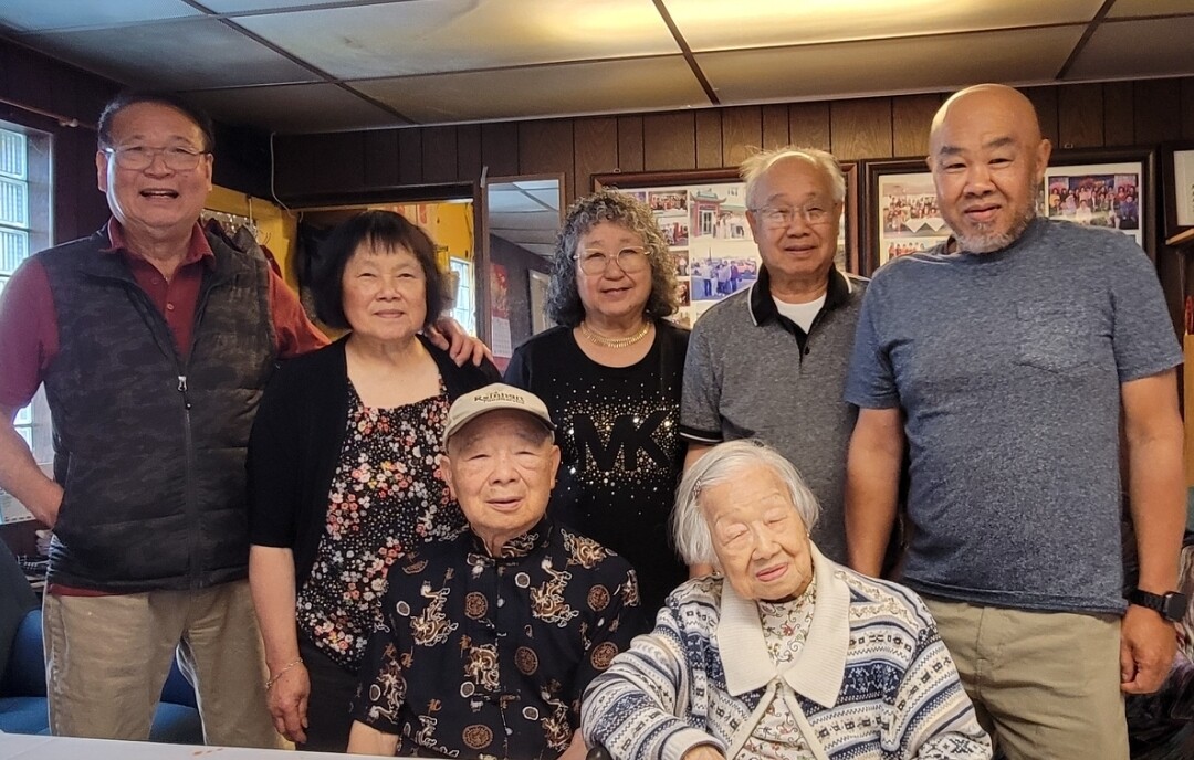 Seven seniors posing together for a group photo in a cozy room, smiling at the camera.