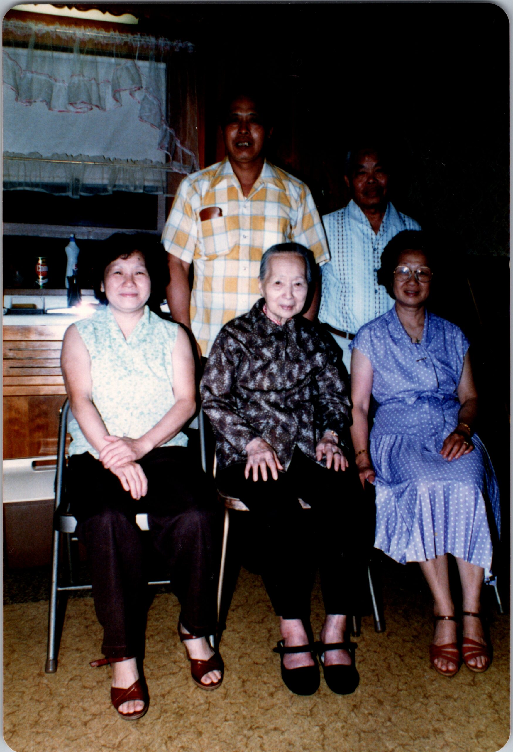Five people posing for a group photo indoors: two men standing behind three women seated in front.