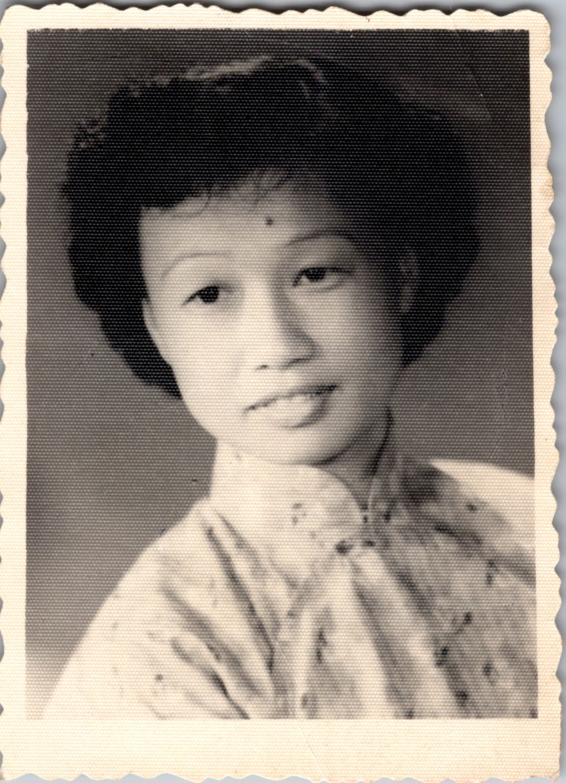 Smiling woman with short dark hair in a light blouse, posed for a studio portrait.