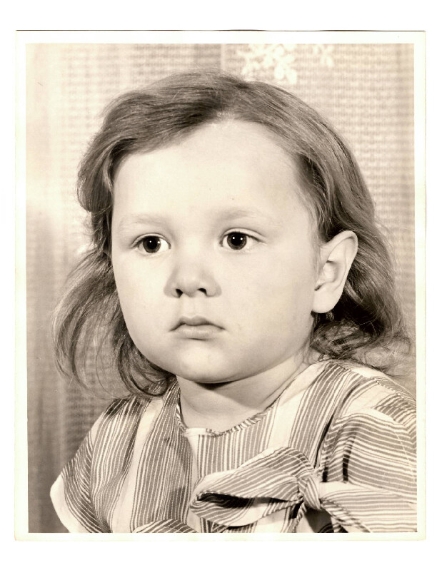 Young child portrait: girl with shoulder-length hair, striped dress, neutral expression.